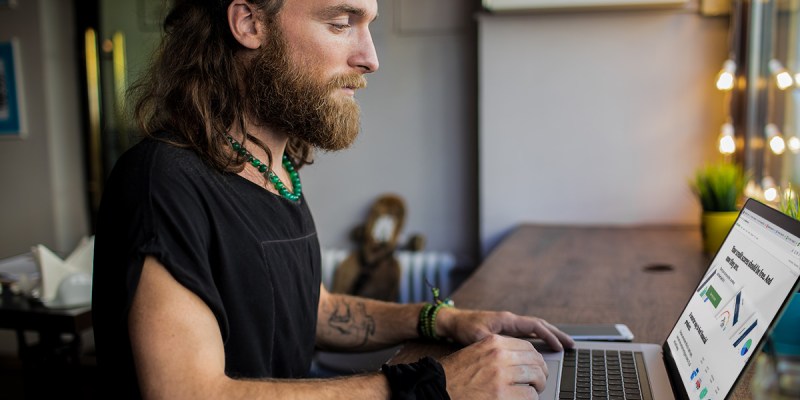 beard, punk, greasy, white guy, computer, poor, in debt, credit, bad credit, tattoos, laptop, table, desk, sad
