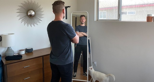 Aspiring Venue Security Guard Practices Crossing Arms in Bedroom for Hours