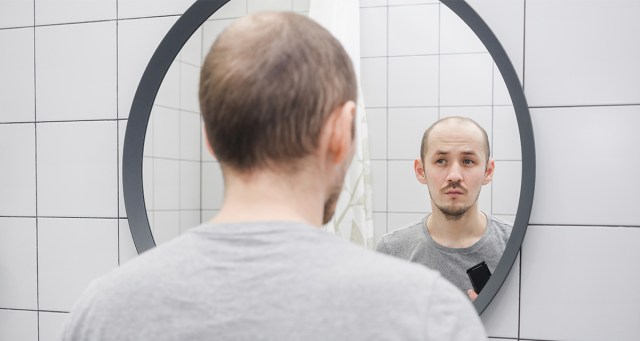 Merch Guy Rehearsing Not Making Eye Contact in Venue Bathroom Mirror